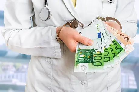 Eine Person in Arztkleidung hält Geldscheine in der Hand.