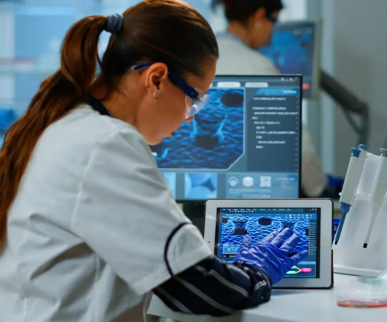 Wissenschaftlerin mit digitalem Tablet bei der Arbeit in einem modernen medizinischen Labor.